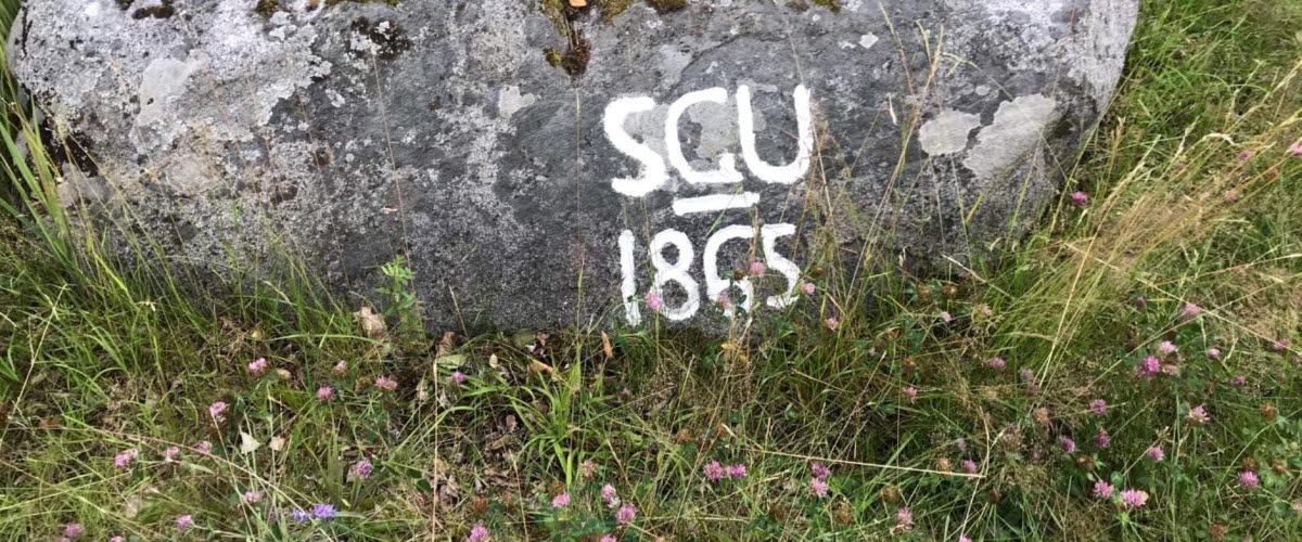 Image of a stone with the painted text "SGU 1865."