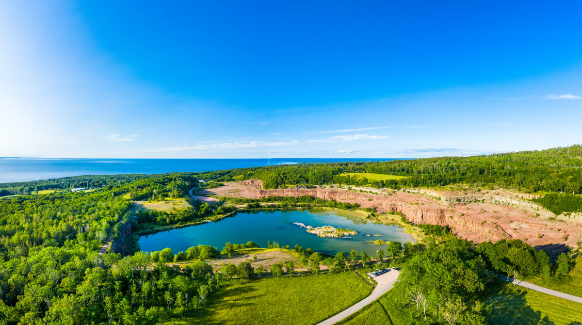 The old limestone quarry filled with clear blue water. The quarry is surrounded by green nature.