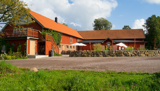 Exteriörbild på Löfwings, röda byggnader med en stenmur framför.