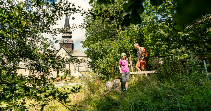 Man och kvinna som vandrar i gröngräset med Varnhems klosterkyrka i bakgrunden.