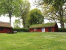 Two red cottages with green grass in front