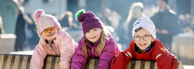 Three kids with winter hats playing at the square in Skövde.