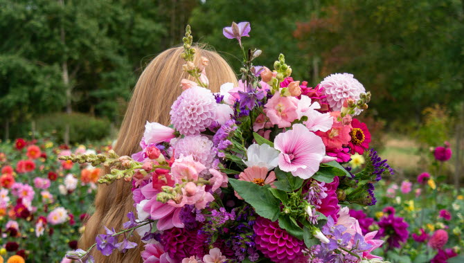 Kvinna som bär på färgglada blommor.