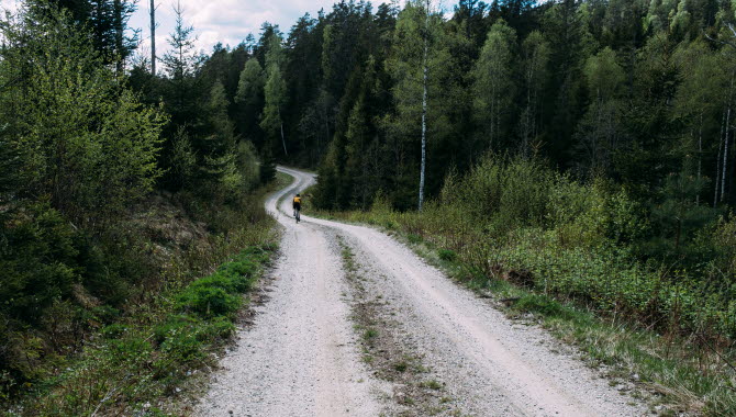 Kvinna cyklar på grusväg i Dalsland