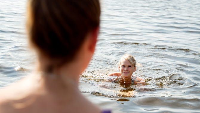 En kvinna badar i en sjö.