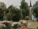 Rabatter med dahlior i olika färger och en klosterkyrka i bakgrunden.