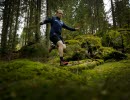 Traillöpare mitt i ett hopp över stockar och stenar utmed traillöpningsspår på Billingen Skövde