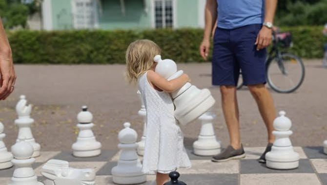 Liten tjej spelar utomhusschack i Hjo Stadspark.