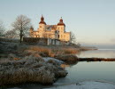 Ett vitt slott vid en sjö i ett vinterlandskap