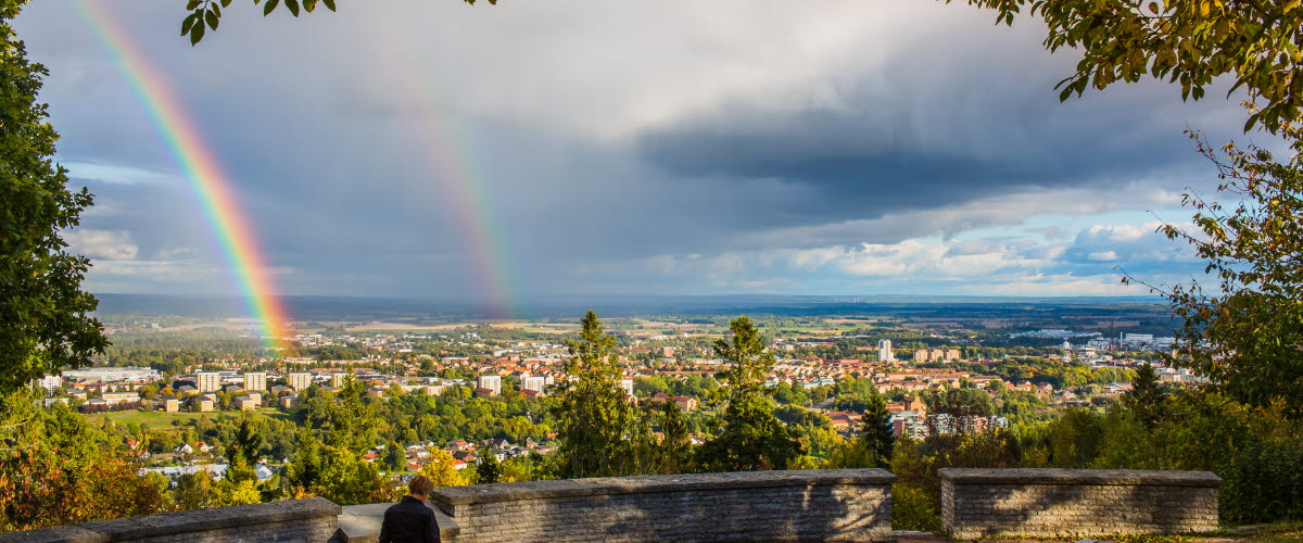 A woman is walking by the vantage point at the mountain Billingen. Two rainbows is visible on the sky.