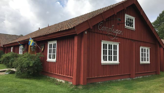 Röd gammaldags träbyggnad med skylt Cesarstugan på gaveln.