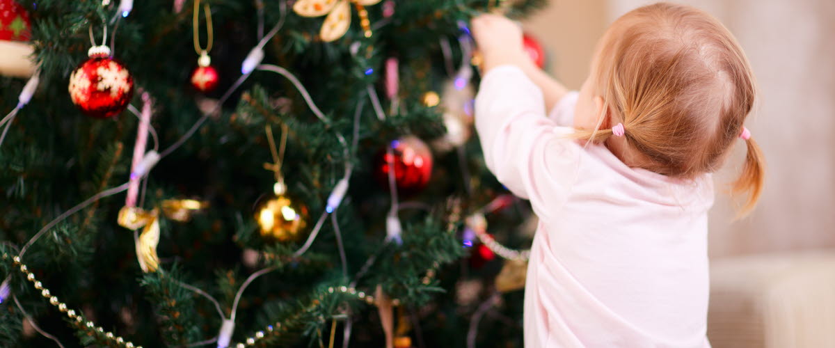 Ung flicka som dekorerar julgranen.
