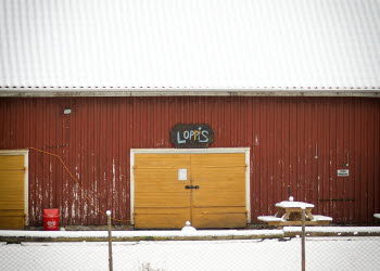 En bild på en gul ladgårdsdörr på en röd ladugård i vinter landskap.