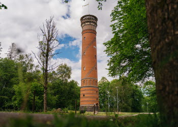 Utsiktstorn i rött tegel med träd och buskar runt omkring.