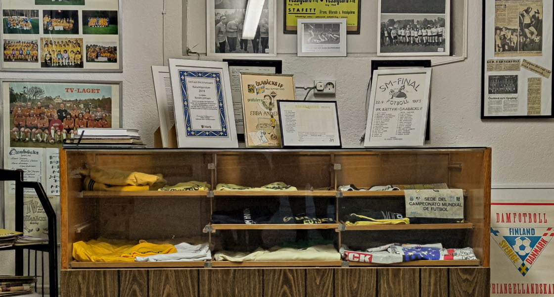 En närbild en köpmansdisk med saker i. På väggarna hänger mängder av fotografier, tidningsartiklar och tavlor.