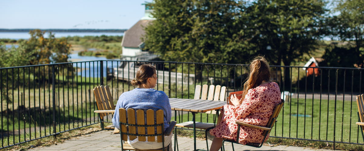 Två personer sitter vid ett bord och tittar ut över Hornborgasjön