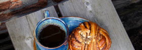 Blå fat med bullar och en blå kaffekopp med kaffe i.