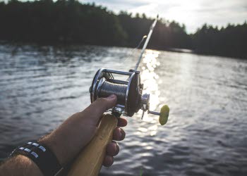Person som håller ett kastspö vid en sjö