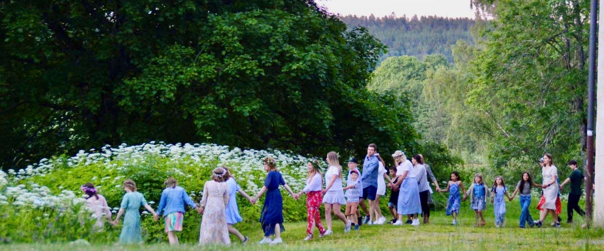 Människor dansar i gräset på midsommarafton.