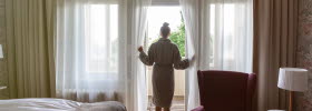 Woman in bathrobe standing in the doorway to the balcony of the hotel room.