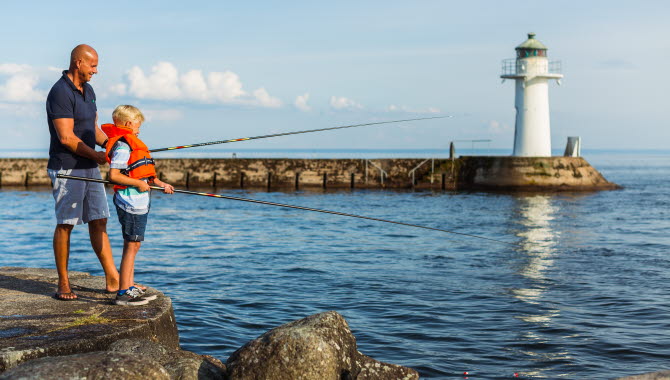 Far och son fiskar i Hjo hamn.