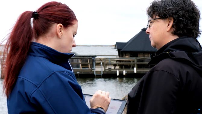 Två kvinnor pratar med varandra i närheten av en sjö