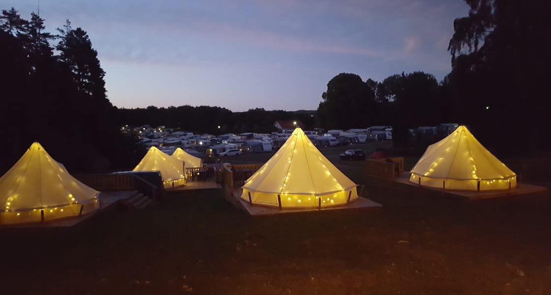 Upplysta glampingtält i kvällsljus