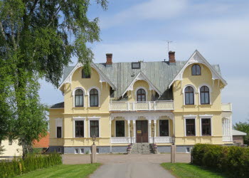 Skövde Vandrarhem som ligger i en gul sekelskiftesvilla med vit snickarglädje.