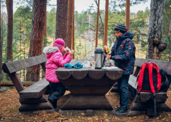 Två personer som äter utomhus på bänk och bord