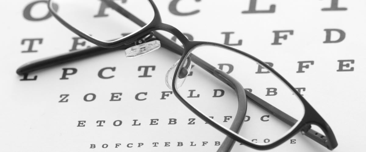Ett par svarta glasögon som ligger på ett syntest med bokstäver.