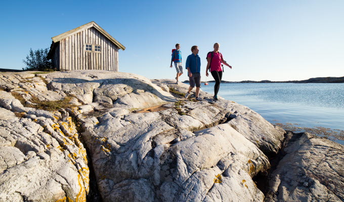 Sällskap vandrar på klipporna vid sjöbod