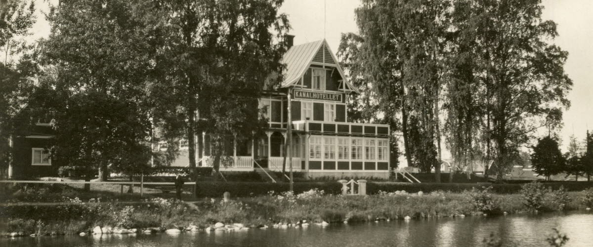 Black and white archive image of a three-story building right next to the Göta Canal.