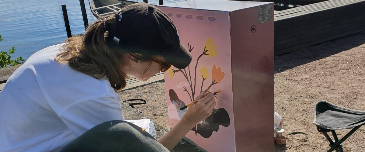 Kvinna målar elskåp i Hjo hamn