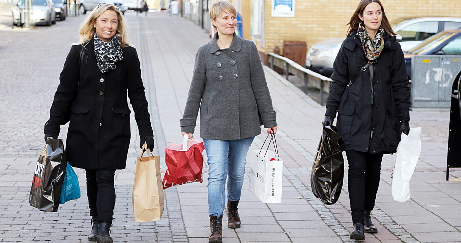 Tre kvinnor som bär på påsar efter shopping.