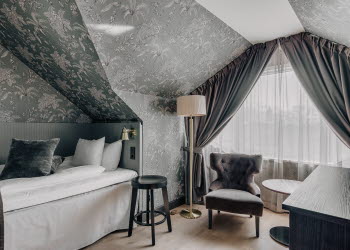 Ett enkelrum med  säng, skrivbord och fåtölj på Skara Stadshotell.