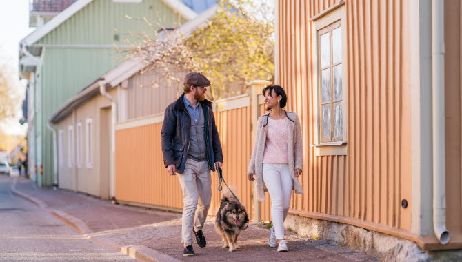 Ett par på vårpromenad med sin hund längs med Långgatan mitt i den gamla trästaden i Hjo.