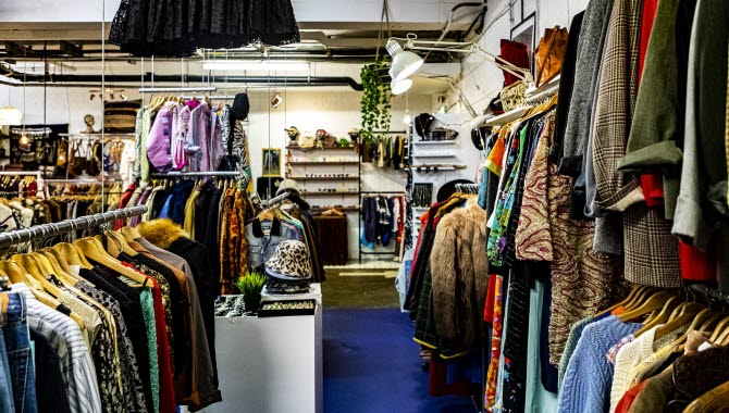 En butik med begagnade kläder som hänger på galgar