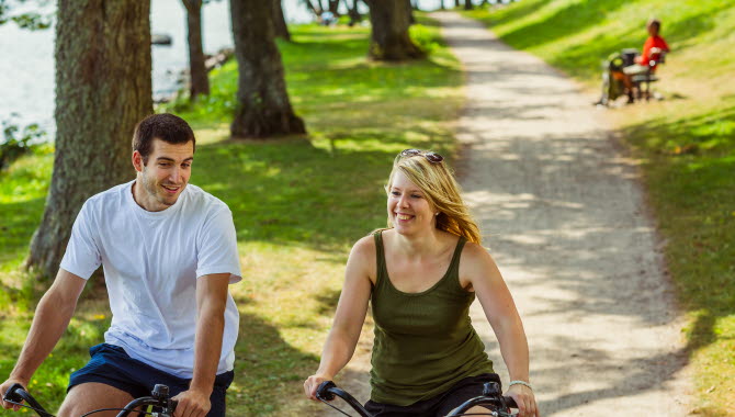 Par som cyklar längs strandpromenaden i Hjo.