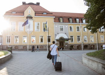 Kvinna går med väska mot hotellbyggnad.