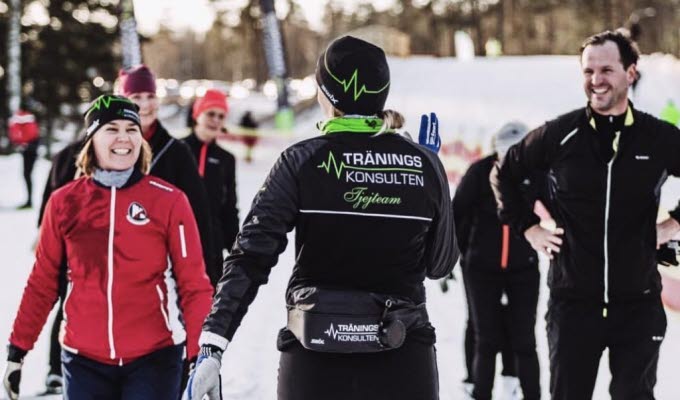 Glada skidåkare i grupp tränar stakåkning utan stavar med ledare