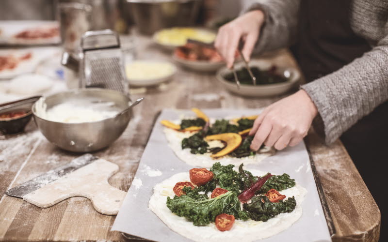 Kvinna lagar pizza hos Kosters Trädgårdar