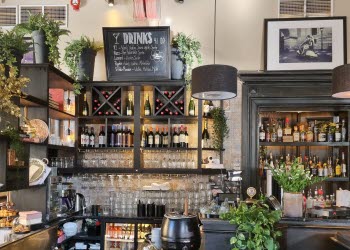 Baren på restaurang, med glas, flaskor och drinkmeny på griffeltavla.