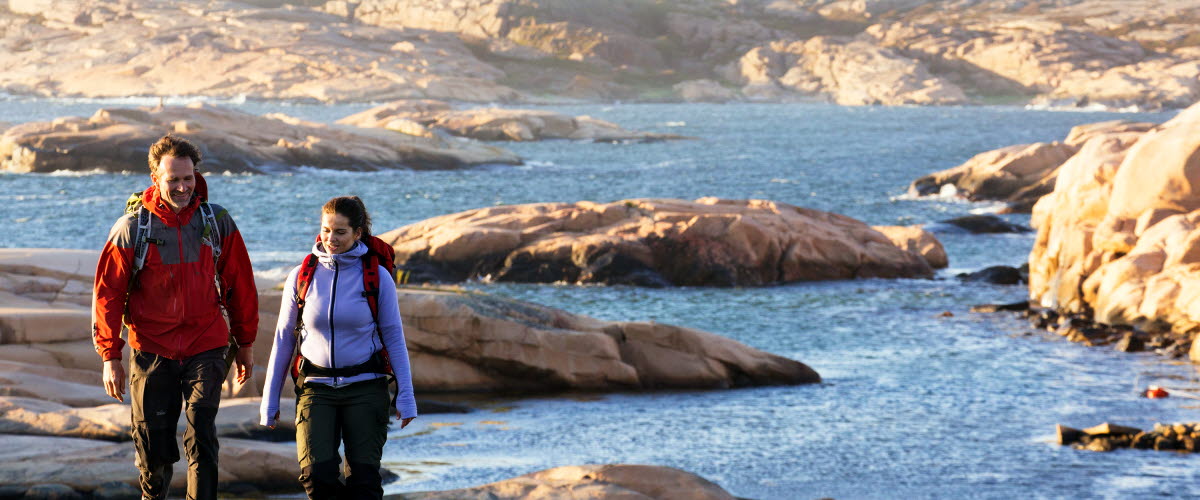 Par vandrar på klipporna med kobbar som bakgrund