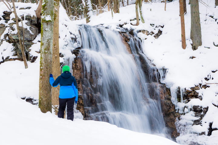 En person står framför Silverfallet, det är vintertid och fallet har frusit. 
