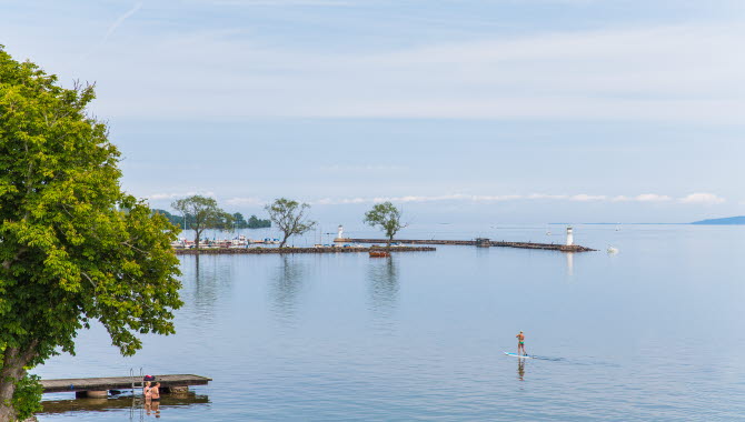 Badande människor i Vättern med vy över Hjo hamn.