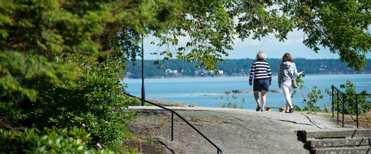 Två personer promenerar vid Vänerns vatten