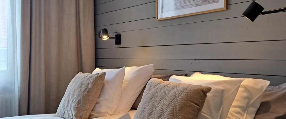 Hotellrum med två sängar mot en vägg med grå träpanel.