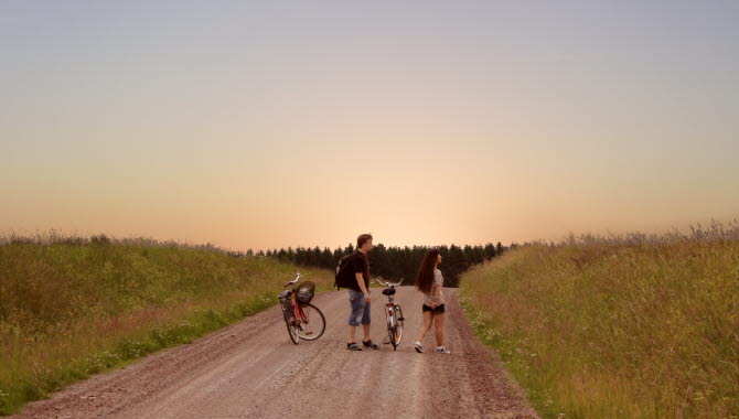 Man och kvinna som står på en grusväg med cyklar bredvid sig.