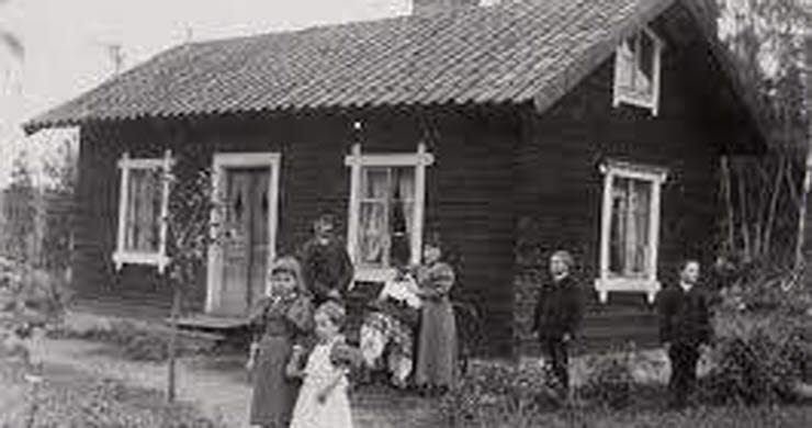 svartvitt fotografi med människor framför en liten stuga