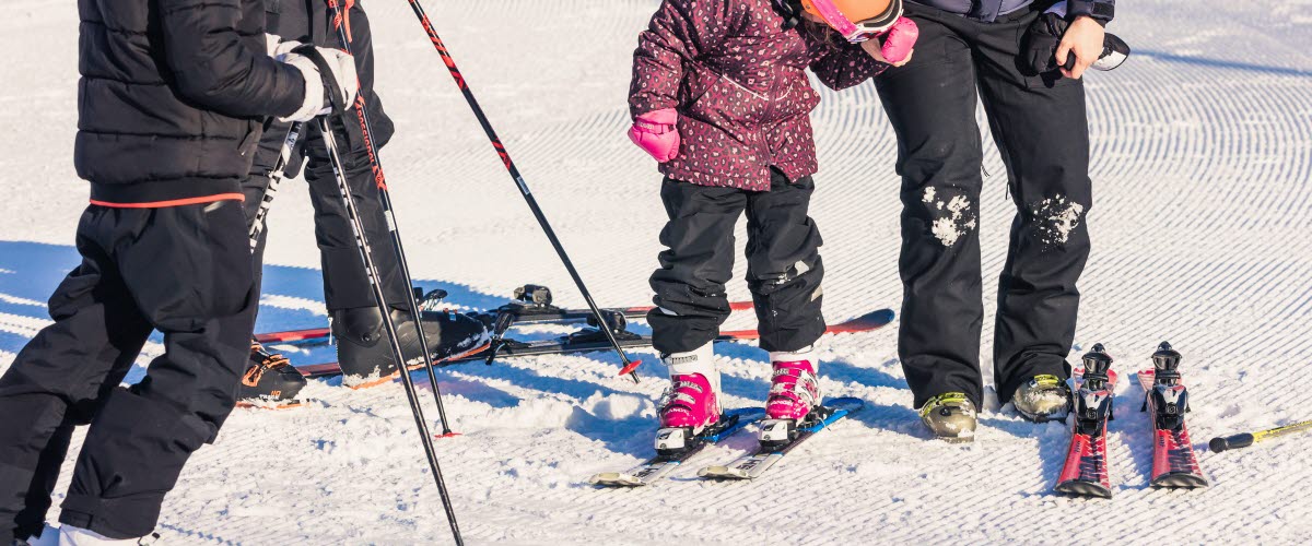 En familj på 4 personer tar på sig sina skidor.
